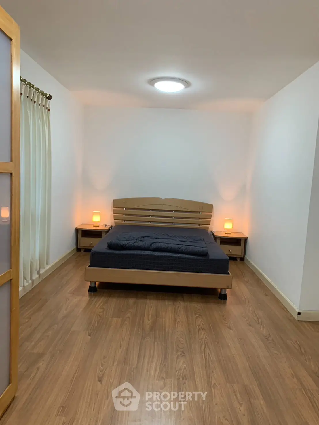 Spacious bedroom with wooden flooring and cozy lighting, perfect for relaxation.