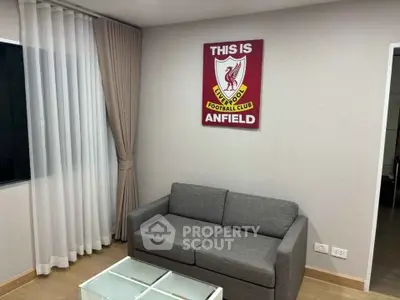Modern living room with stylish gray sofa and glass coffee table, featuring a Liverpool FC wall decor.