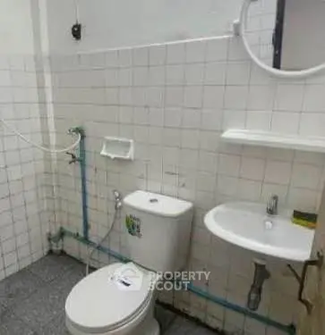 Compact bathroom with white tiles and basic fixtures, ideal for small spaces.