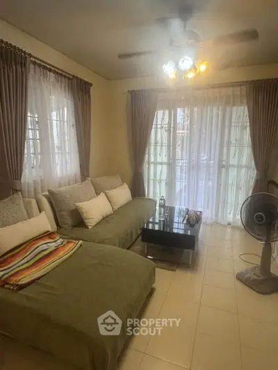 Cozy living room with large windows and comfortable seating, perfect for relaxation.