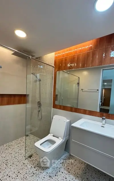 Modern bathroom with sleek fixtures and glass shower enclosure in a contemporary home.