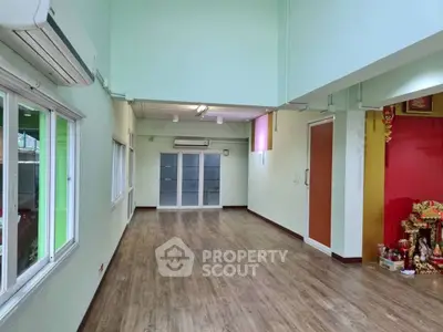 Spacious open-plan room with wooden flooring and large windows, perfect for versatile use.