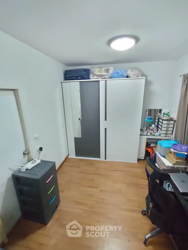 Cozy bedroom with wooden flooring and modern wardrobe, ideal for comfortable living.