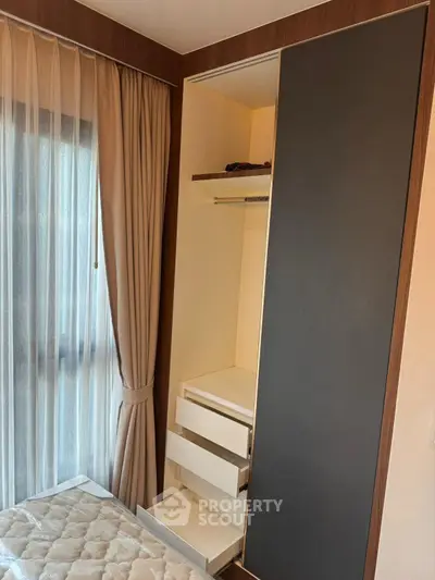 Modern bedroom with built-in wardrobe and large window with elegant curtains.