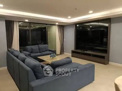 Spacious modern living room with blue sofas and large TV, perfect for relaxation.