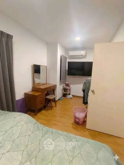 Cozy bedroom with modern decor, featuring a large TV and stylish wooden furniture.