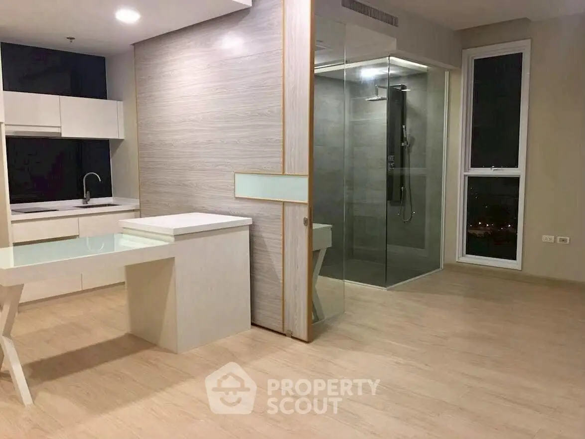 Modern open-plan kitchen with sleek design and glass shower enclosure.