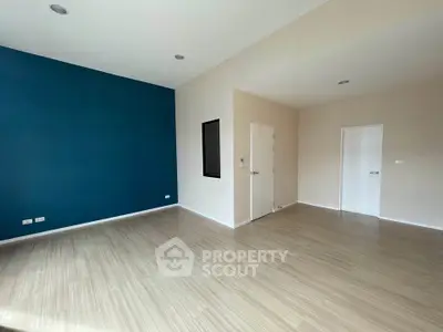 Spacious empty room with modern flooring and accent wall, perfect for customization.