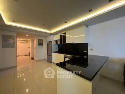 Modern kitchen with sleek black countertops and open layout in spacious apartment.