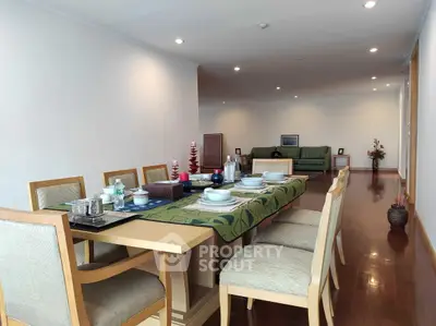 Spacious dining area with elegant table setting and cozy living room in the background.