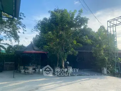 Spacious outdoor area with lush greenery and seating, perfect for relaxation.