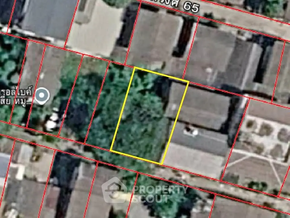 Aerial view of a residential plot outlined in yellow, surrounded by houses and greenery.