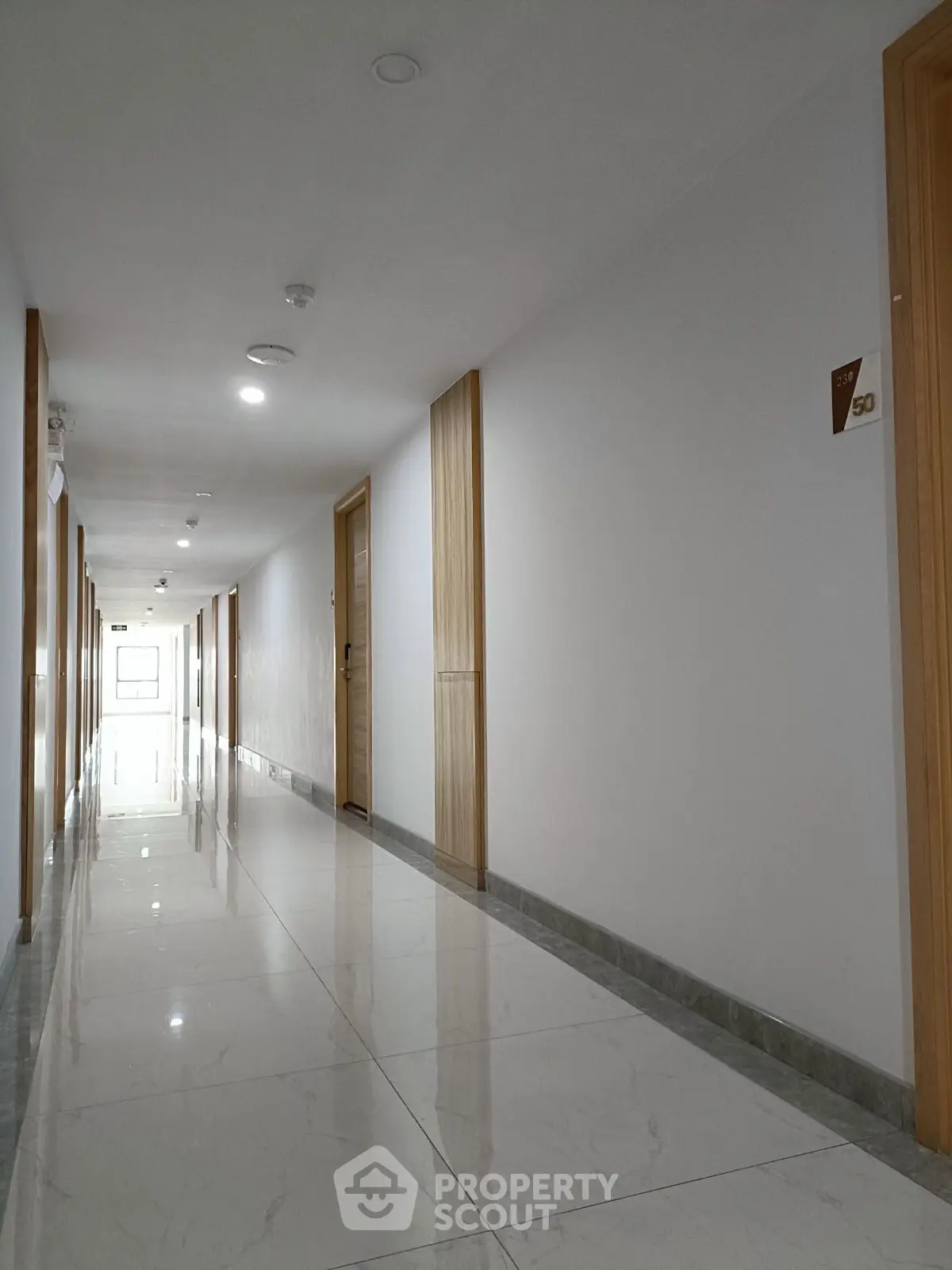 Modern apartment hallway with sleek marble flooring and wooden doors