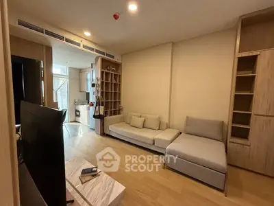 Modern living room with cozy seating and open kitchen layout in a stylish apartment.