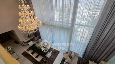 Luxurious high-ceiling living room with elegant chandelier and panoramic city view.