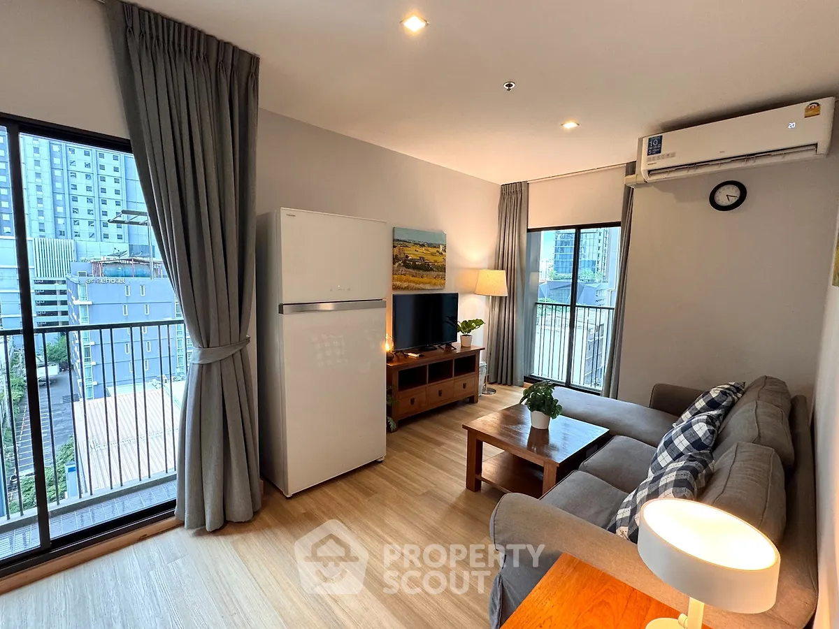 Modern living room with balcony view, featuring cozy sofa, wooden furniture, and natural light.