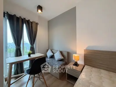 Cozy bedroom with modern decor and natural light, featuring a small desk and stylish seating area.