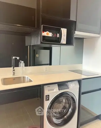 Modern kitchen with sleek appliances and integrated washing machine in stylish apartment.