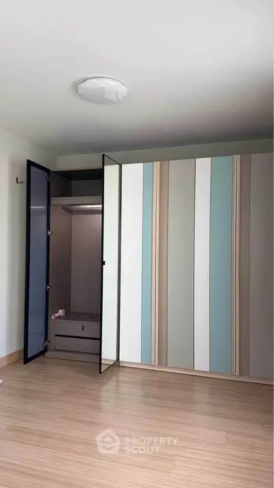 Modern bedroom with stylish wardrobe and wooden flooring