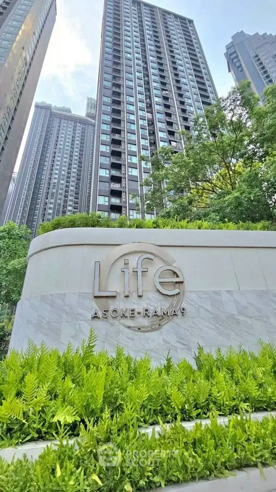 Modern high-rise building Life Asoke-Rama 9 with lush greenery and elegant entrance signage.