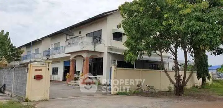 Spacious two-story building with gated entrance and lush greenery, ideal for residential or commercial use.