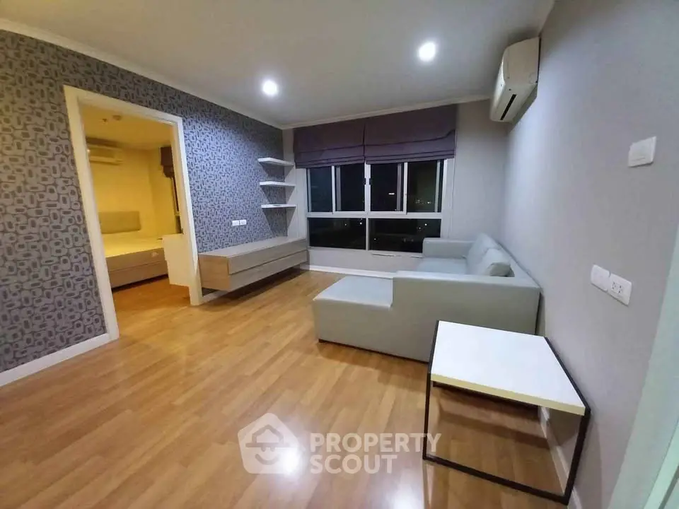 Modern living room with wooden flooring, stylish wallpaper, and cozy furniture in a well-lit apartment.