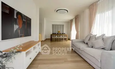 Spacious living room with modern decor and natural light, featuring a cozy sofa and elegant dining area.