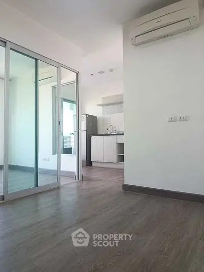 Modern apartment interior with sleek kitchen and spacious living area featuring wooden flooring.