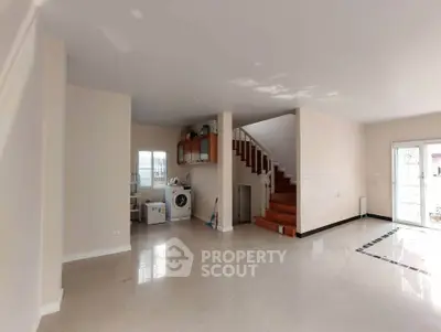 Spacious open-plan living area with staircase and washing machine, ideal for modern family living.