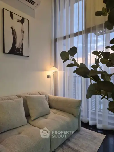 Stylish living room with cozy sofa and elegant decor, featuring floor-to-ceiling windows and modern art.