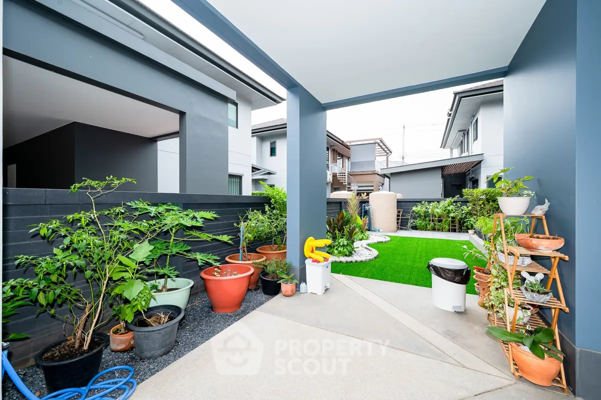 Modern garden area with potted plants and artificial grass in a contemporary home exterior.