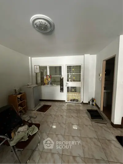Spacious living area with tiled flooring and natural light, featuring a cozy seating arrangement and modern decor.