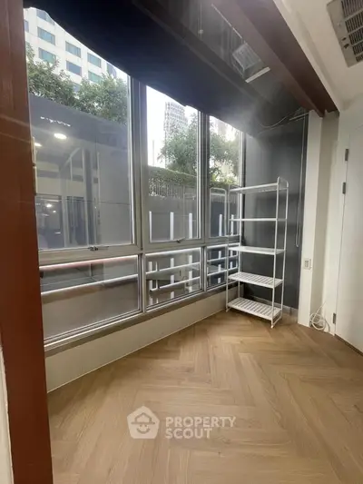 Bright room with large windows and wooden flooring, ideal for versatile use.