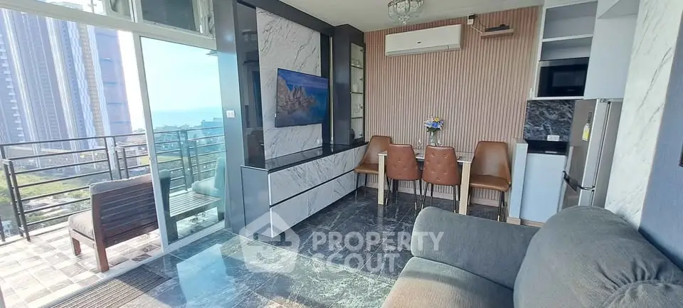 Modern living room with balcony and sea view, featuring stylish decor and natural light.