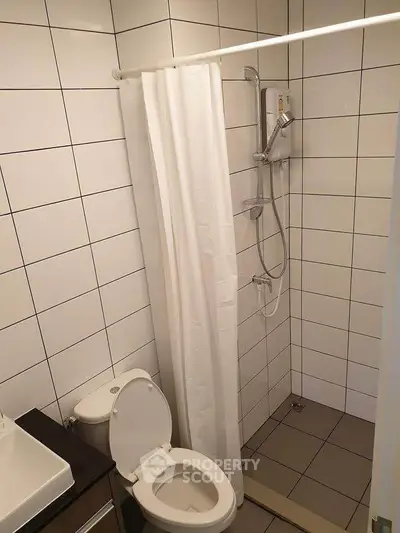 Compact bathroom with shower and toilet in modern tiled design