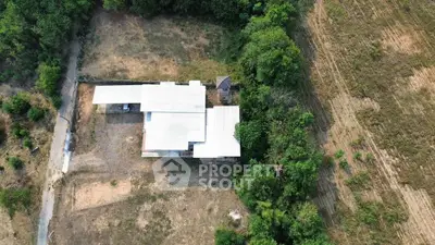 Aerial view of a secluded property surrounded by lush greenery and open fields.