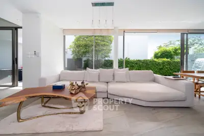 Spacious modern living room with large windows and stylish furniture, offering a serene garden view.