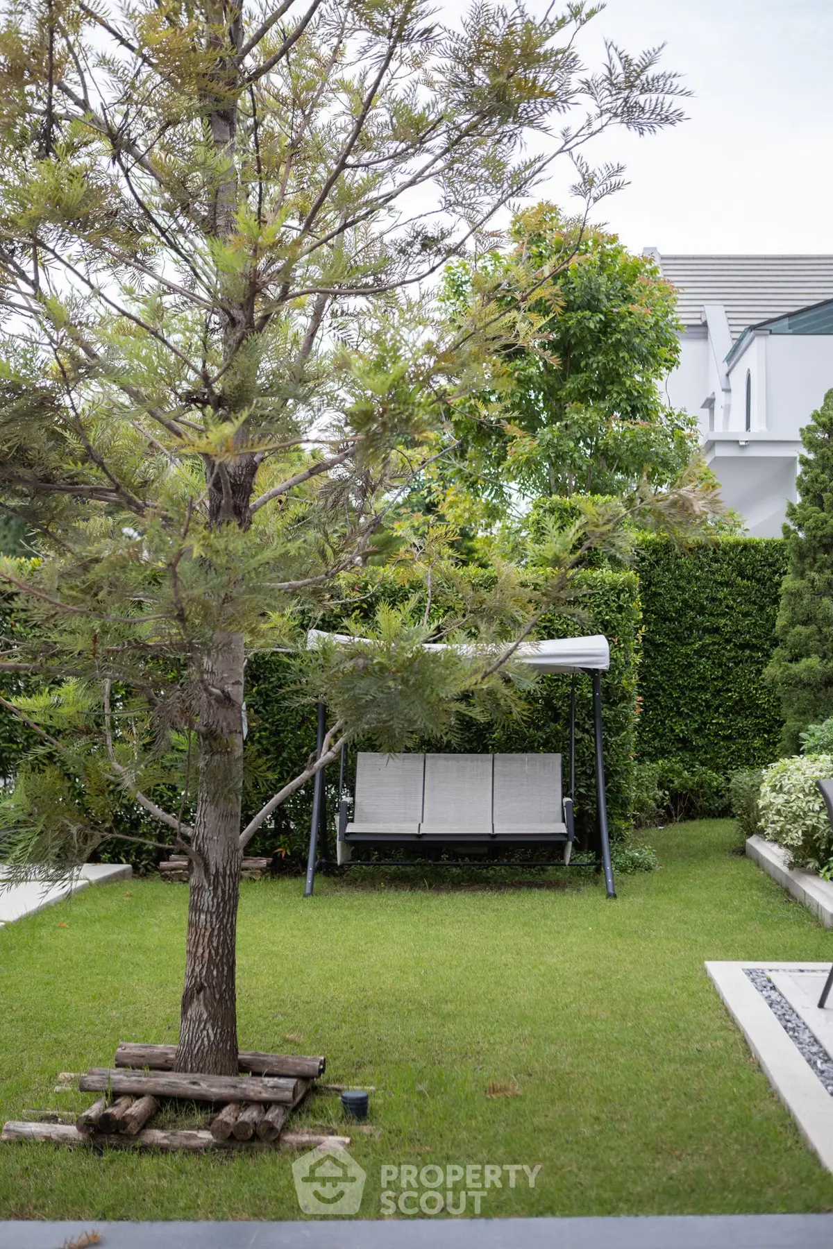 Charming garden with swing and lush greenery in modern residential area.