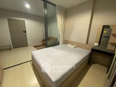 Cozy bedroom with modern furnishings and glass partition in a stylish apartment.
