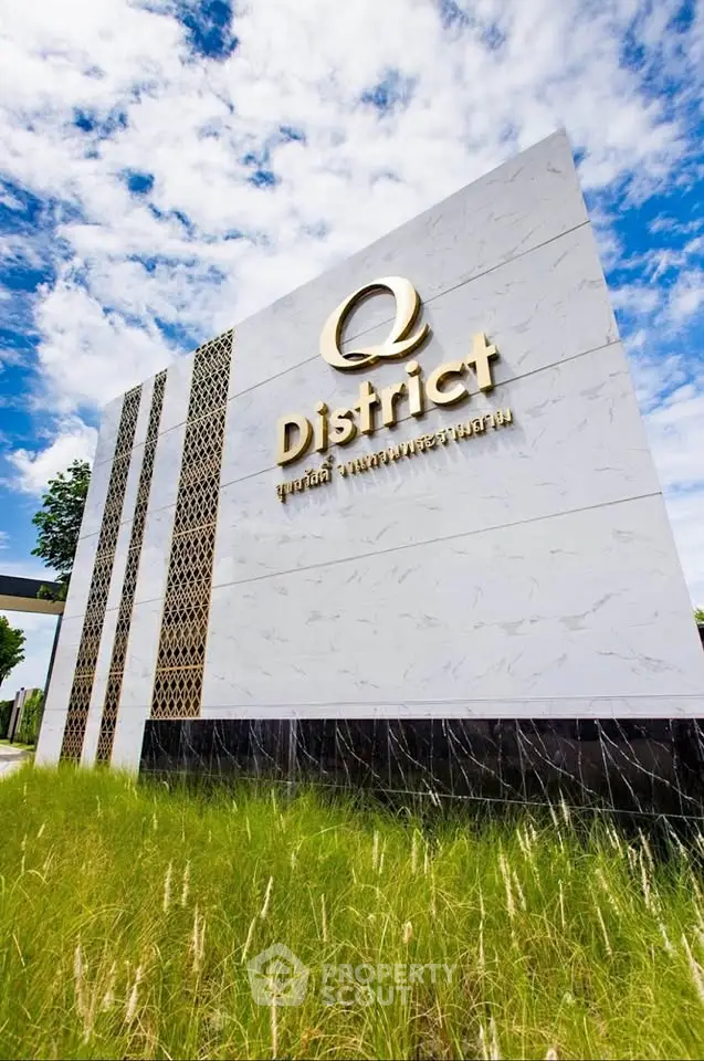 Modern real estate development sign with elegant design and lush landscaping under a vibrant sky.