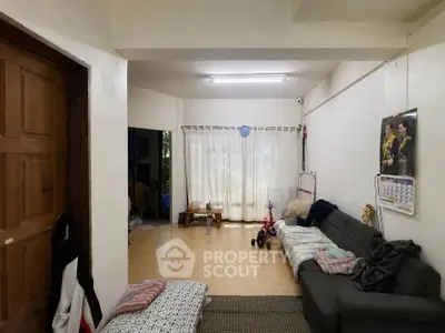 Cozy living room with natural light, wooden door, and comfortable seating area.