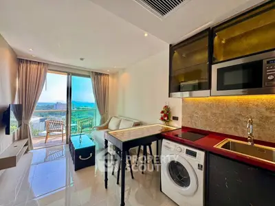 Modern living room with kitchen, featuring washing machine, microwave, and scenic balcony view.