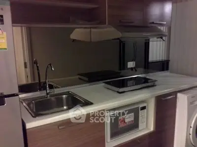 Modern kitchen with sleek appliances and wooden cabinetry, featuring a built-in microwave and electric stove.