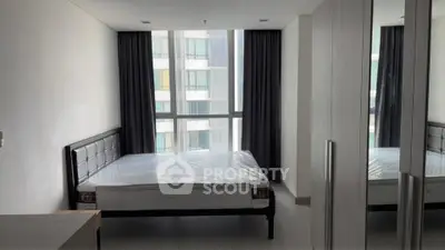 Spacious bedroom with large window and modern furnishings in a high-rise apartment.
