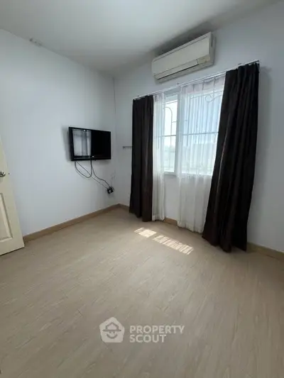 Bright empty room with air conditioning and mounted TV, perfect for customization.