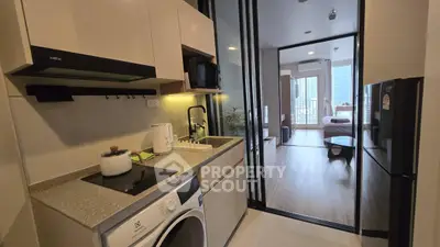 Modern kitchen with washing machine and open layout leading to a bright living area with balcony view.