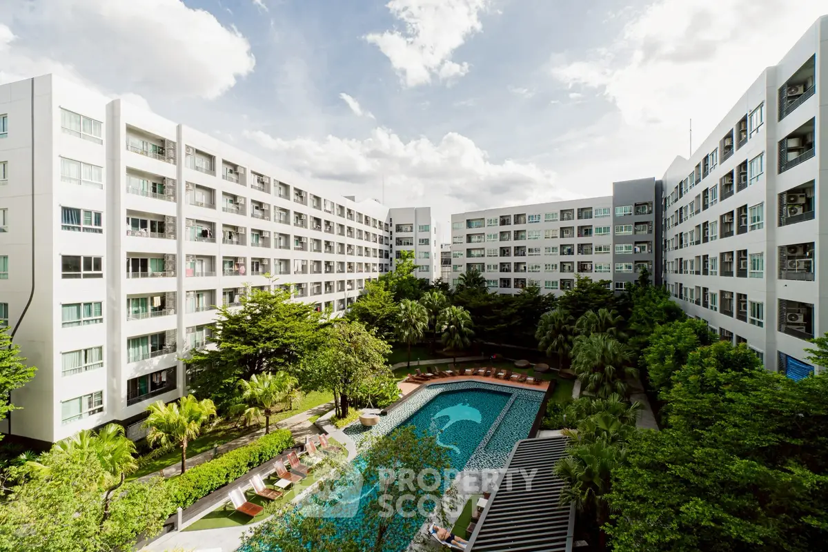 Modern apartment complex with lush garden and inviting pool area under a clear blue sky.