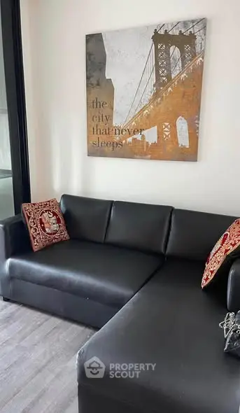 Modern living room with black leather sectional sofa and stylish wall art.