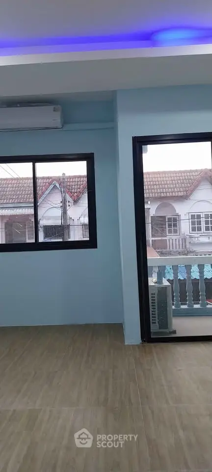 Spacious room with large windows and balcony access, featuring modern flooring and ambient lighting.