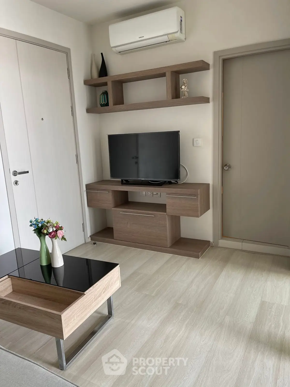 Modern living room with sleek furniture and wall-mounted TV, featuring minimalist design.